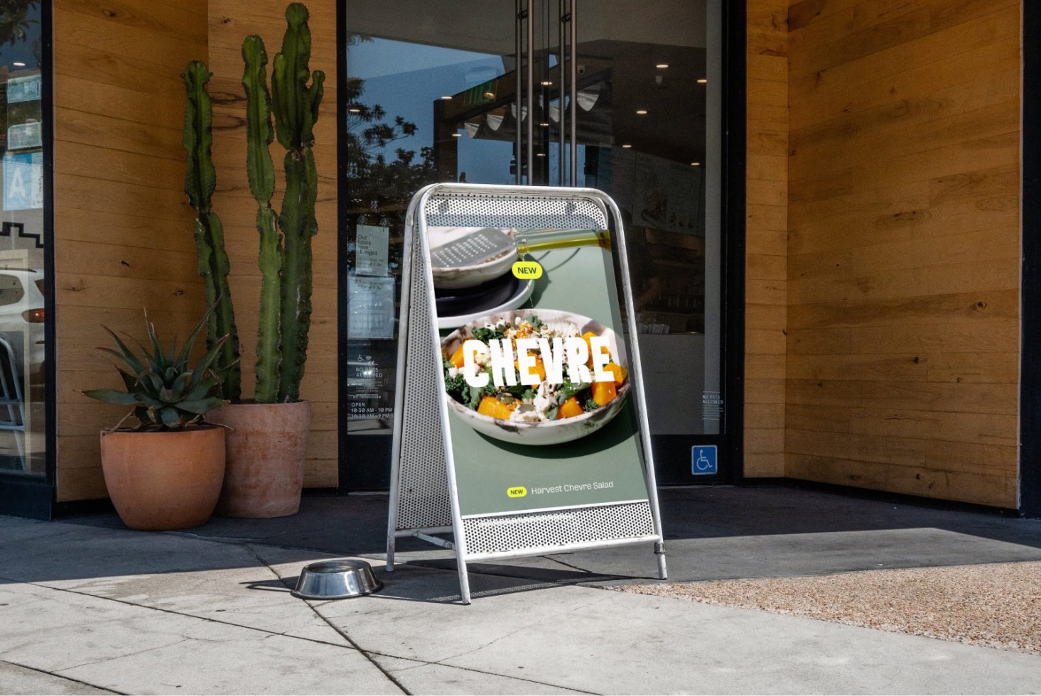 Sidewalk signboard mockup outside a cafe displaying new salad advertisement with urban setting and potted plants, ideal for storefront design presentation.